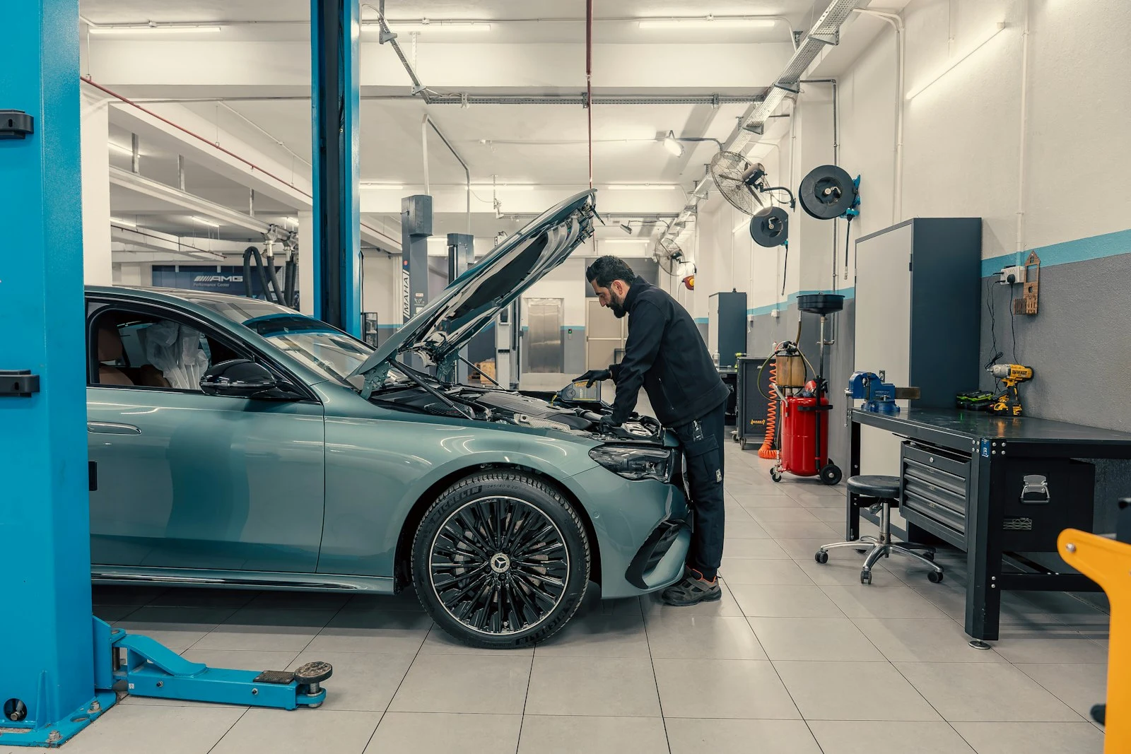 Mechanic working under the bonnet of a vehicle in a clean workshop